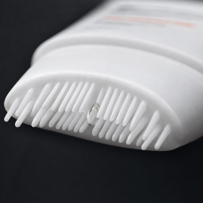 Close-up of the silicone scalp comb applicator teeth with a bead of serum